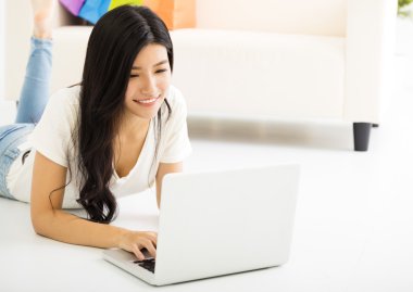 oturma odasında dizüstü bilgisayar ile mutlu bir genç kadın