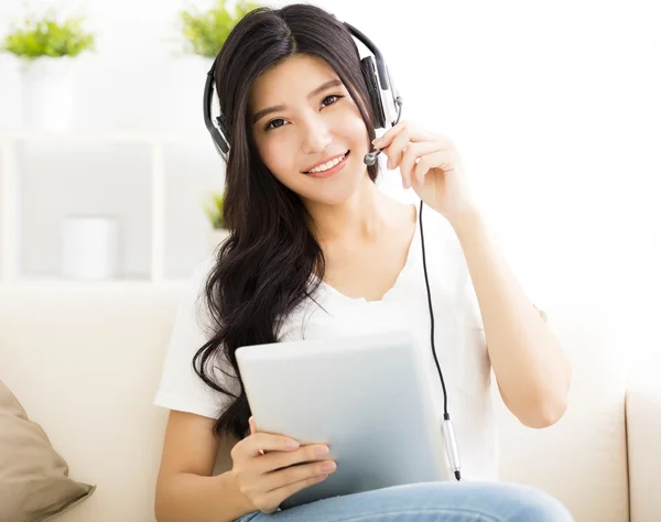 Mujer joven con auriculares y tablet en la sala de estar —  Fotos de Stock