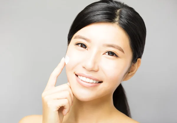 Mujer joven aplicando tratamiento de crema cosmética en la cara —  Fotos de Stock