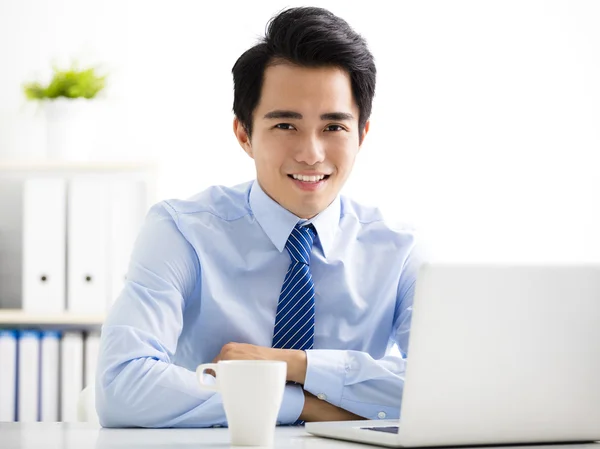 Smiling young business man working on laptop — Stock Photo, Image