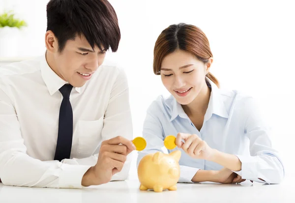 Homem de negócios e mulher colocando moeda no banco porquinho — Fotografia de Stock