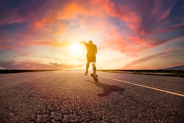 日没を背景に道路を走っている男は — ストック写真