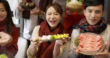 Hot pot restoranında çeşitli yiyecekler gösteren genç bir grup.