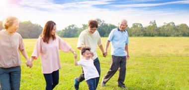 Parkta yürüyen üç nesil Asyalı aile.