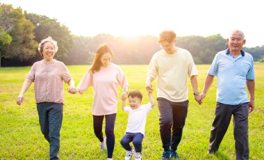 Parkta yürüyen üç nesil Asyalı aile.