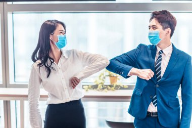 İş adamları tıbbi maske takıyor ve el sıkışmak yerine dirsekleriyle vuruyorlar. 