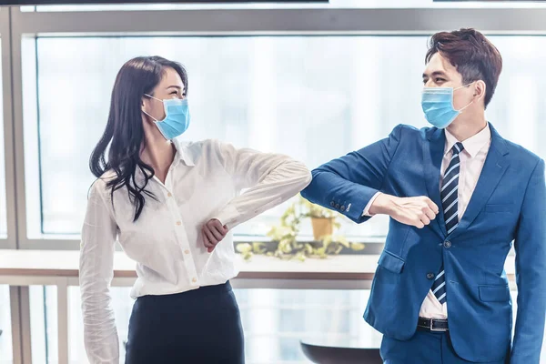 business people wearing medical mask and   striking with their elbows instead of  handshake