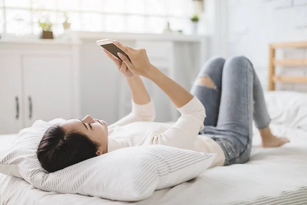 Genç Bir Kadın Cep Telefonunu Izliyor Evde Yatakta Uzanıyor — Stok fotoğraf