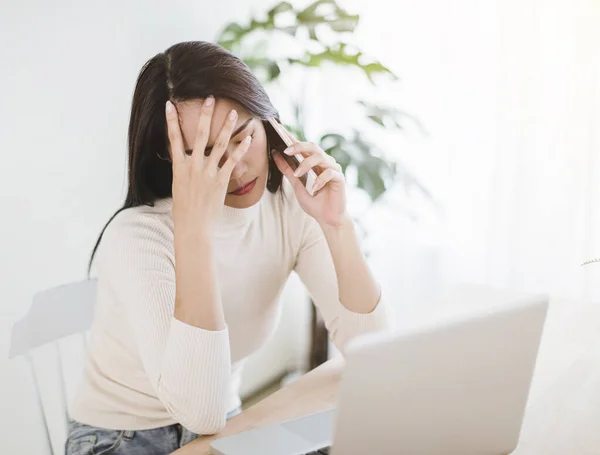 压力很大的年轻女人在笔记本电脑上工作 在总公司打电话 — 图库照片