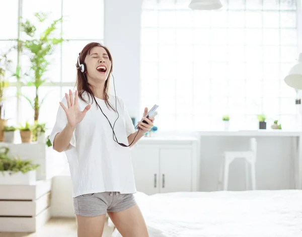 Mujer Joven Emocionada Sosteniendo Teléfono Móvil Cantando Bailando Casa —  Fotos de Stock