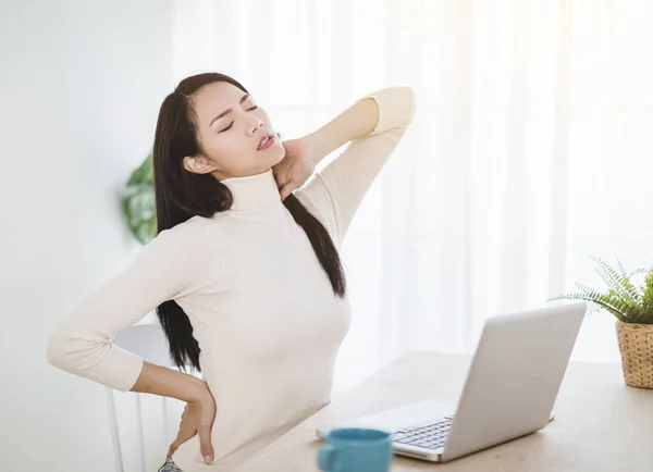 young woman  with neck pain and massaging  neck while working in  office at home