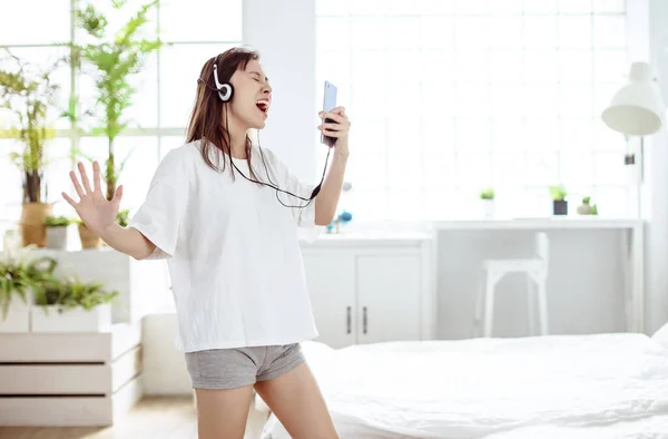 Opgewonden Jonge Vrouw Met Mobiele Telefoon Zingen Dansen Thuis — Stockfoto