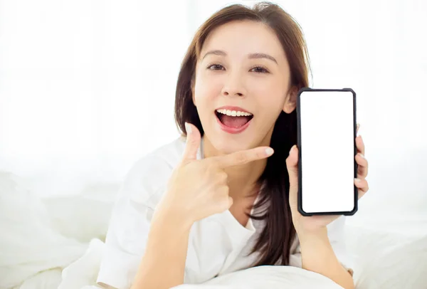 Glad Ung Kvinna Visar Smart Telefon När Ligger Sängen — Stockfoto