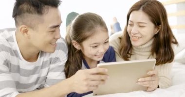  Mutlu aile evdeki yatak odasında dijital tablet kullanıyor.