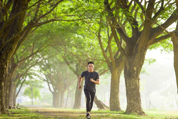 Genç Adam Parkta Koşuyor Cep Telefonuyla Müzik Dinliyor — Stok fotoğraf