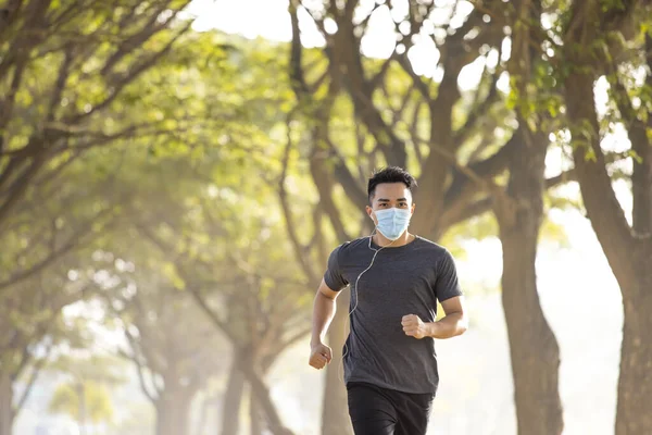 young man in face mask and running in the park