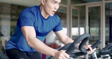 Spor salonundaki adam bisiklet üzerinde egzersiz ve eğitim yapıyor.