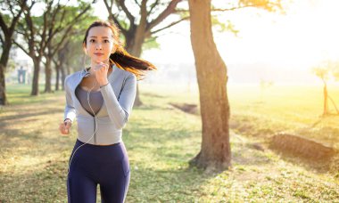 Güzel Asyalı genç bayan sabah parkta koşuyor.