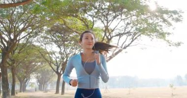 Güzel genç bir kadın sabah parkta koşuyor.