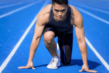 Yarış pistindeki erkek sporcu koşmaya hazır.