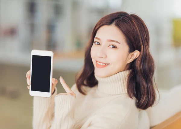 Młoda Kobieta Wskazując Smartfon Pusty Ekran Domu — Zdjęcie stockowe