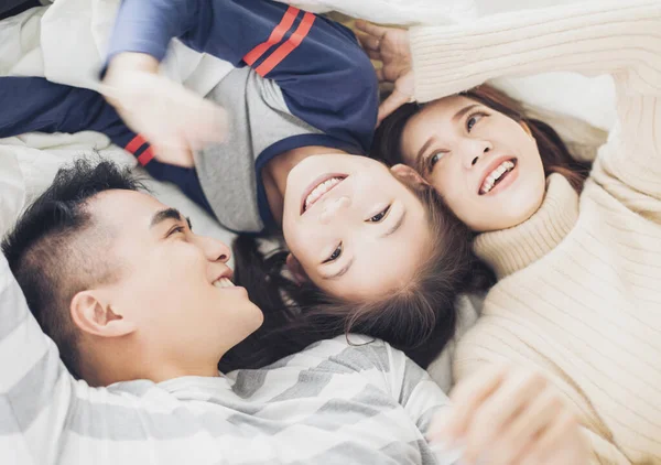幸せな家族がベッドに横になって遊ぶ — ストック写真