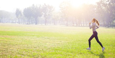Genç ve güzel bir kadın çim tarlasında koşuyor.