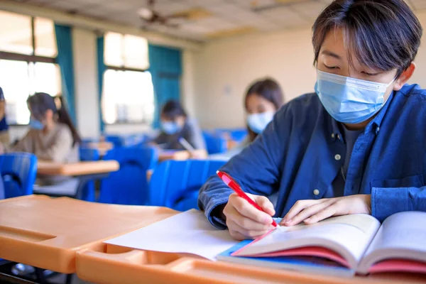 Group of students wearing protection masks and studying in classroom