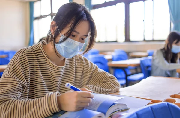 Teenager students wearing protection masks and studying in classroom