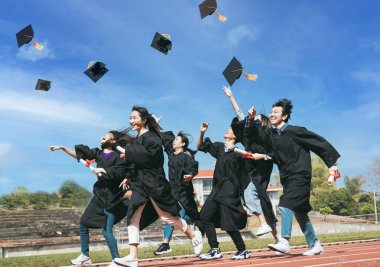 Kutlama için mezuniyet şapkalarını havaya fırlatan mutlu öğrenciler.