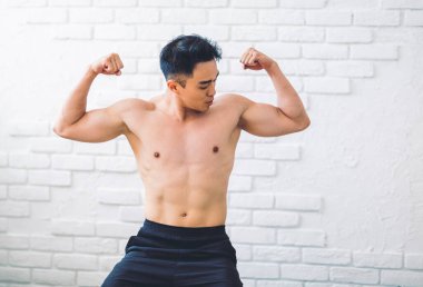 Evde egzersiz yapan kaslı Asyalı genç adam.