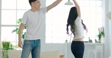 Evdeki oturma odasında dans eden mutlu genç çift. 