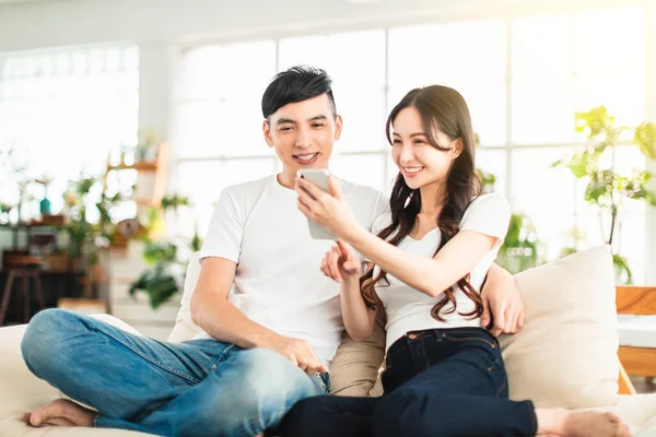 Happy Young Couple Embracing While Looking Mobile Phone Living Room — Stock fotografie