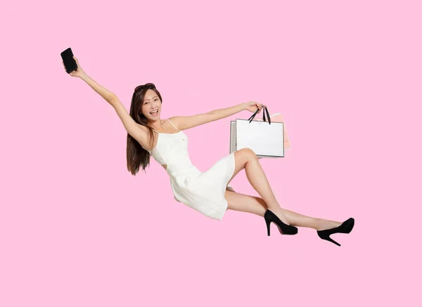Happy Young Woman Holding Mobile Phone Shopping Bags While Flying — Stock Photo, Image