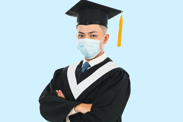 コロナウイルスパンデミックの際に顔マスクをした若い男性の卒業生は — ストック写真