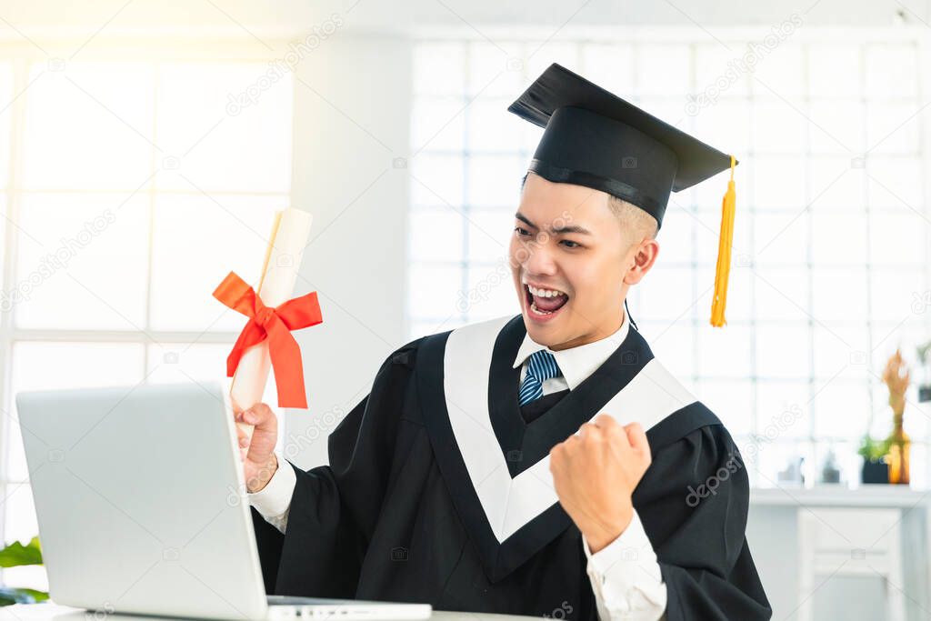 Happy  male graduation watching the  laptop and holding diploma and celebrating success 