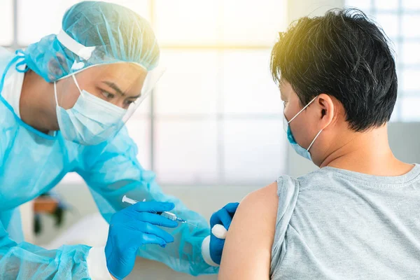 男性患者にワクチン注射を行う注射器でウイルス病から守る顔保護医療マスクを着用した医師 — ストック写真