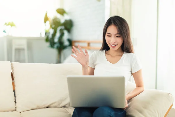 年轻女性在家工作 坐在沙发上使用笔记本电脑进行电子通勤 并与同事视频聊天 — 图库照片