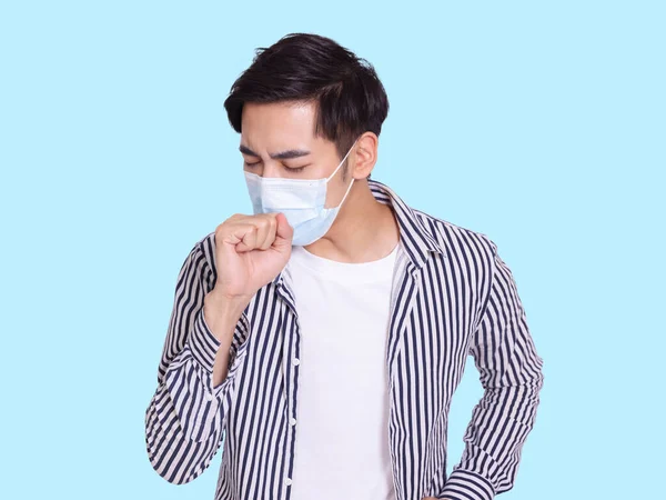 若い男が咳をし 感染を防ぐために保護医療マスクを身に着けている — ストック写真