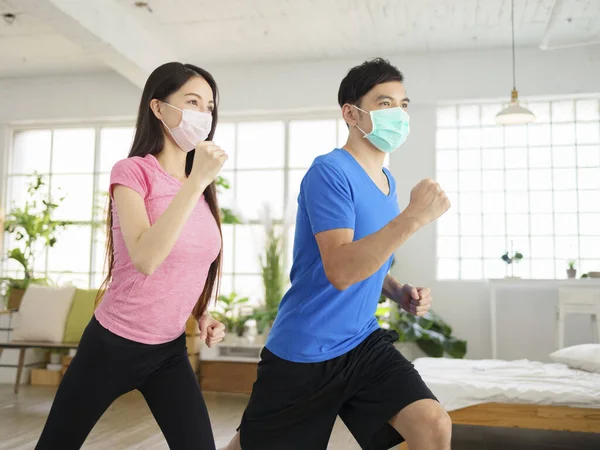 Pareja Joven Está Haciendo Entrenamiento Fitness Usando Máscara Médica Casa — Foto de Stock