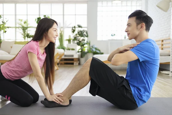 Young Woman Helping Young Man Crunches Home — 图库照片