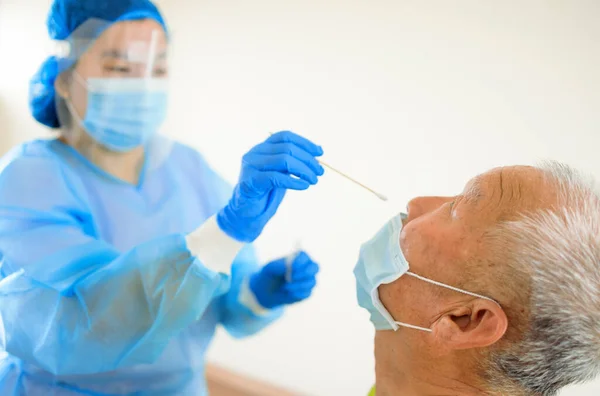 潜在的に感染した老人からコロナウイルスのサンプルのために綿棒を取っている医療従事者 — ストック写真