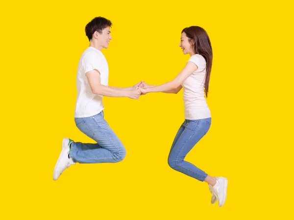 Young Couple Jumping Air Holding Hands Isolated Yellow Background — Stock Photo, Image