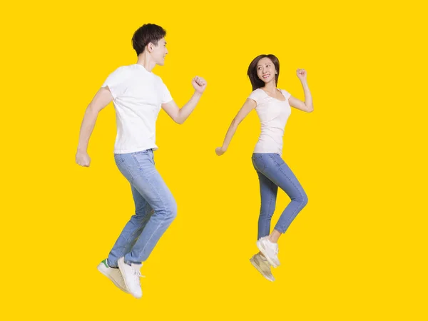 Young Couple Jumping Looking Each Other Isolated Yellow Background — Stock Photo, Image