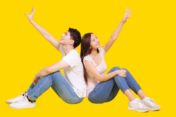 Young Couple Sitting Back Back Grabing Something Isolated Yellow Background — Stock Photo, Image