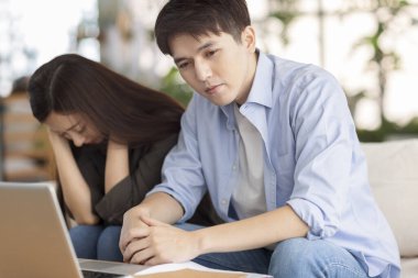 Evde dizüstü bilgisayar kullanan stresli çift.