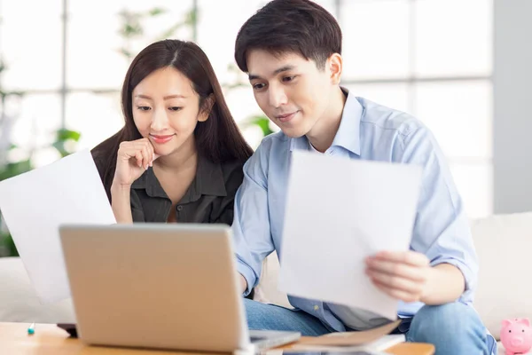 Suami Muda Dan Istri Memegang Dokumen Dan Menggunakan Laptop Rumah — Stok Foto