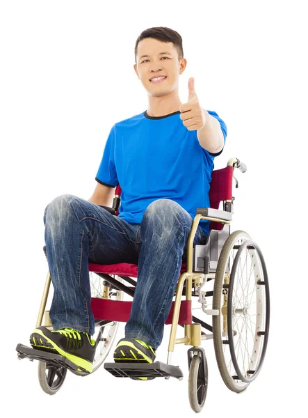 Feliz joven sentado en una silla de ruedas y el pulgar hacia arriba — Foto de Stock