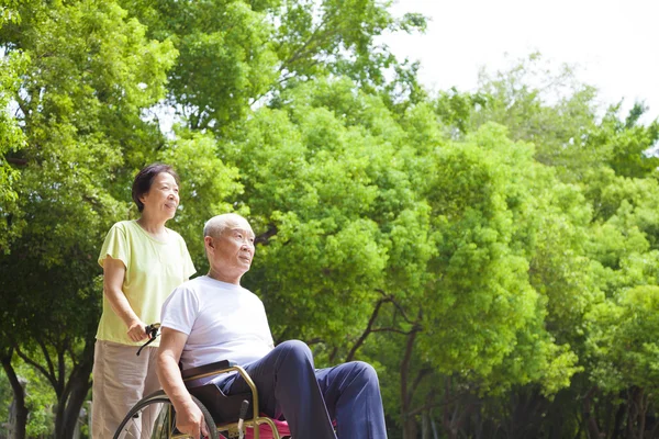 Азіатський старший людини, що сидить на інвалідному візку з дружиною — стокове фото