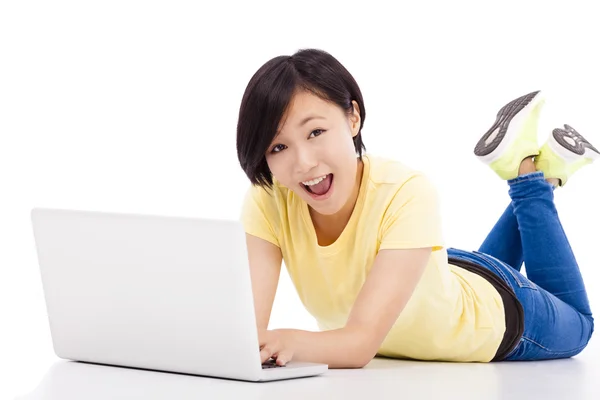 Feliz chica joven acostada en el suelo con un ordenador portátil —  Fotos de Stock